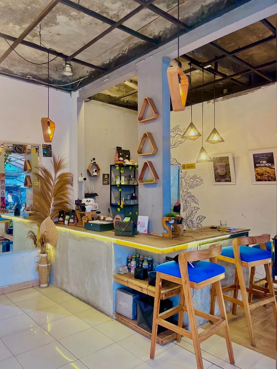 Bar counter Coffee Space dengan kursi biru dan lampu gantung geometris