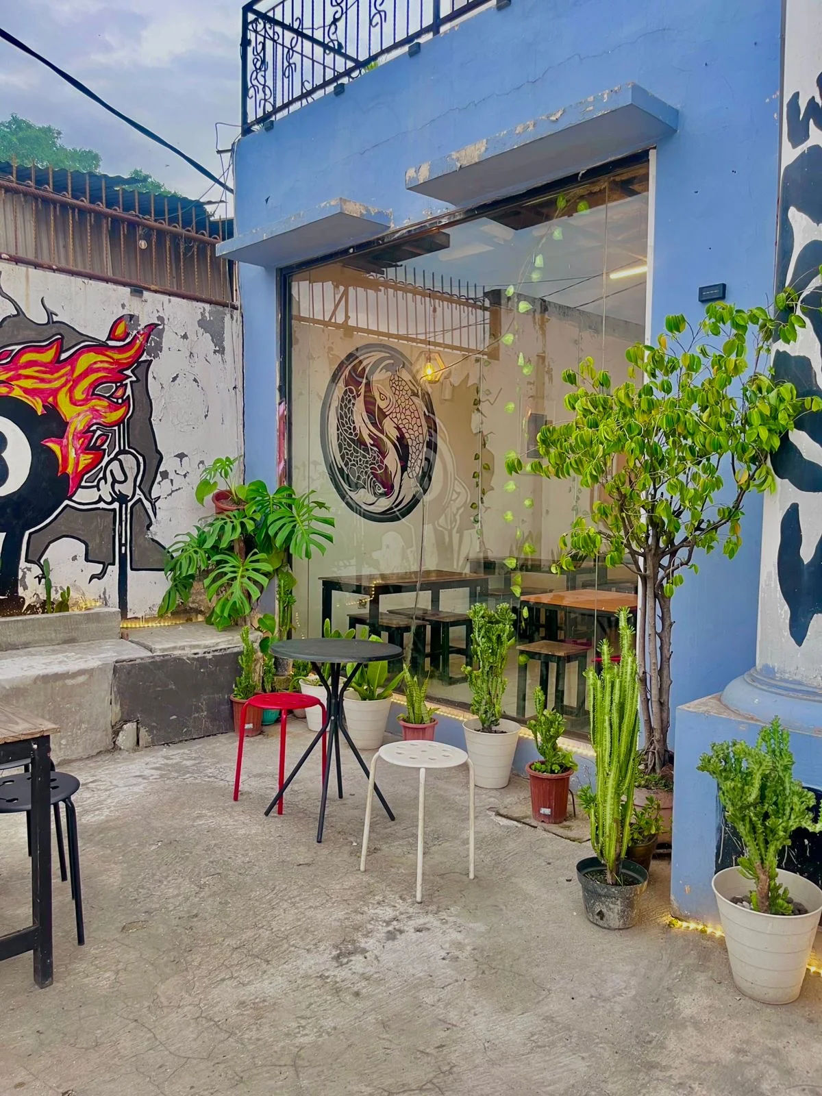 Muka bangunan Coffee Space berwarna biru kobalt dengan mural dan kaktus